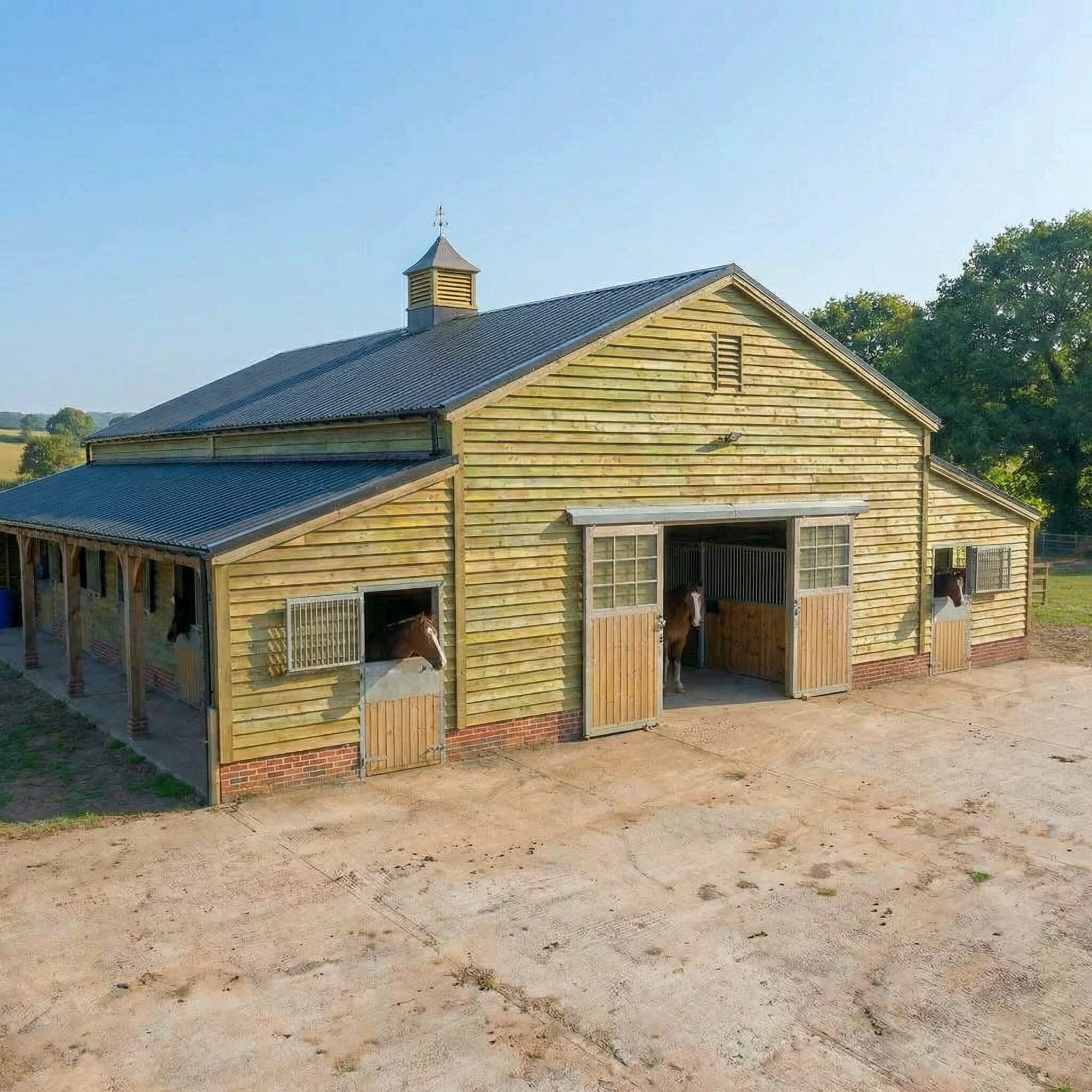 A large wooden American-style barn with an internal central aisle, multiple horse stalls, and sliding main doors.