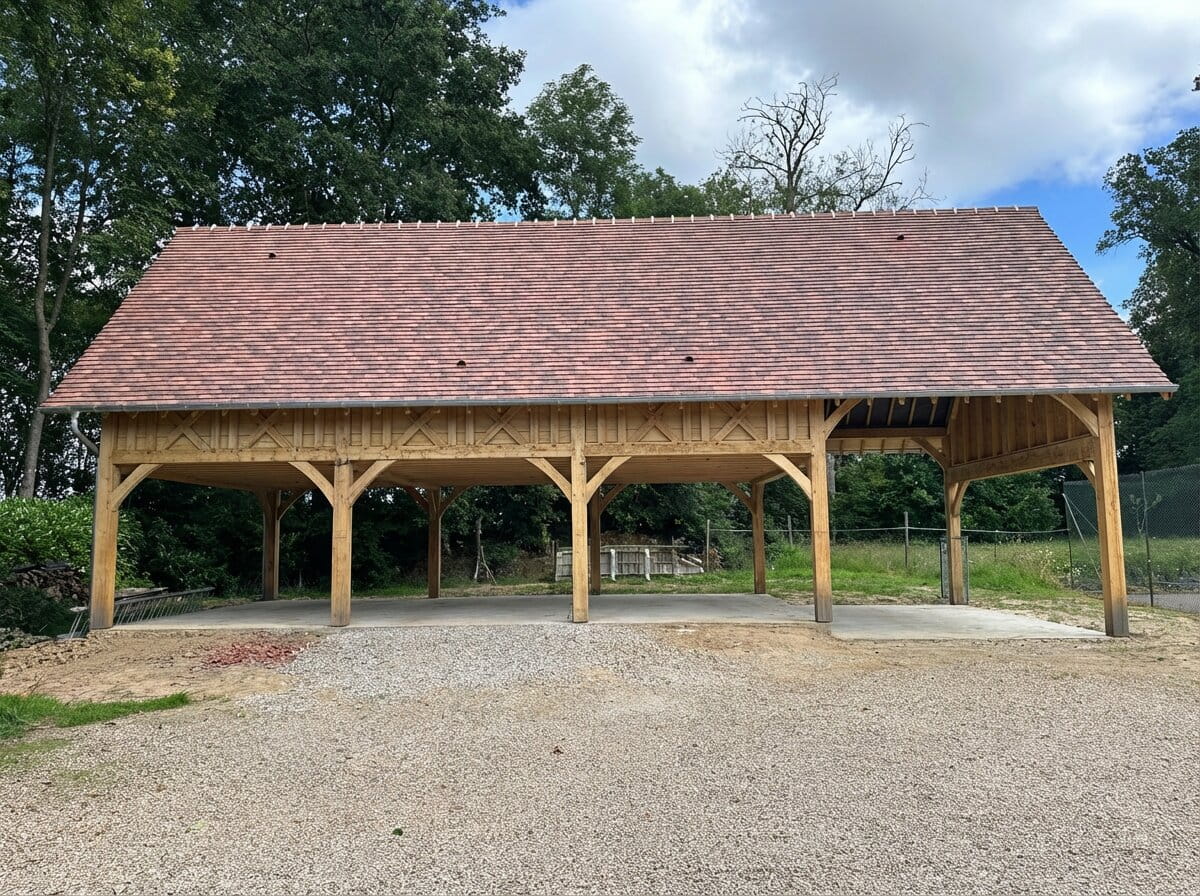 A long, four-bay timber garage complex with a red-tiled roof under construction on a gravel and concrete base.