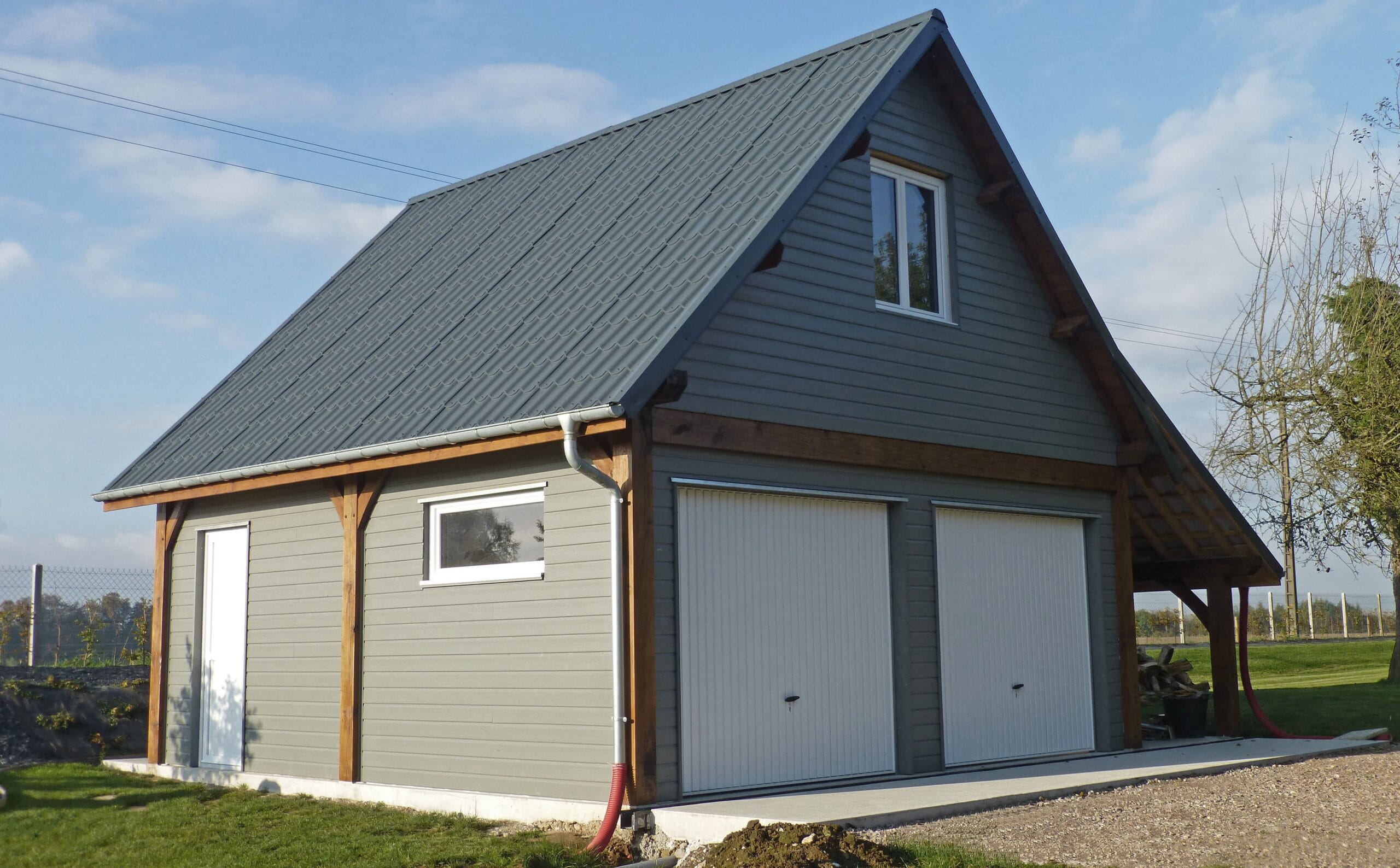 A gray-cladded two-story timber garage with white garage doors and a room above, shown alongside DIY and full-build service options.
