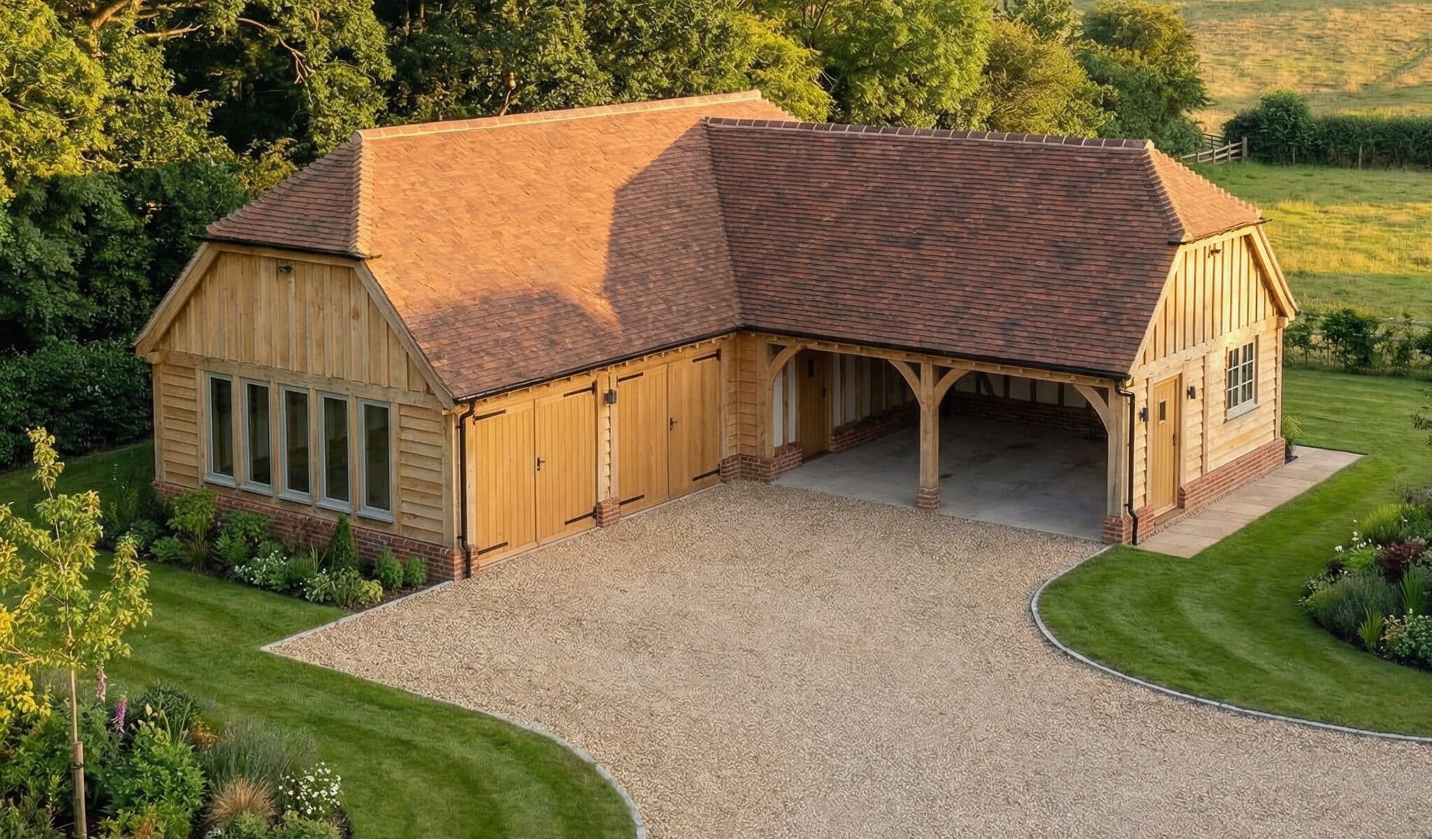 A large L-shaped heavy structural timber garage complex with multiple bays, integrated workshop windows, and a red-tiled roof on a luxury estate.